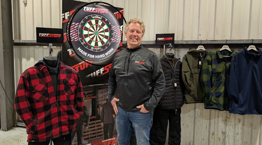 TuffStuff Workwear’s regional sales manager Mark McGovern standing with TuffStuff jackets and a dart board