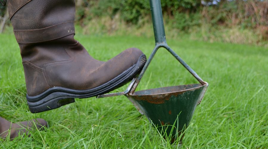 wellie boot stepping on soil testing device in the grass